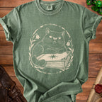 Green t-shirt with a distressed cream print of a cat sitting on a book.