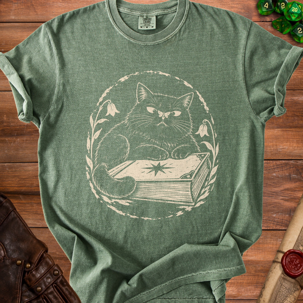 Green t-shirt with a distressed cream print of a cat sitting on a book.