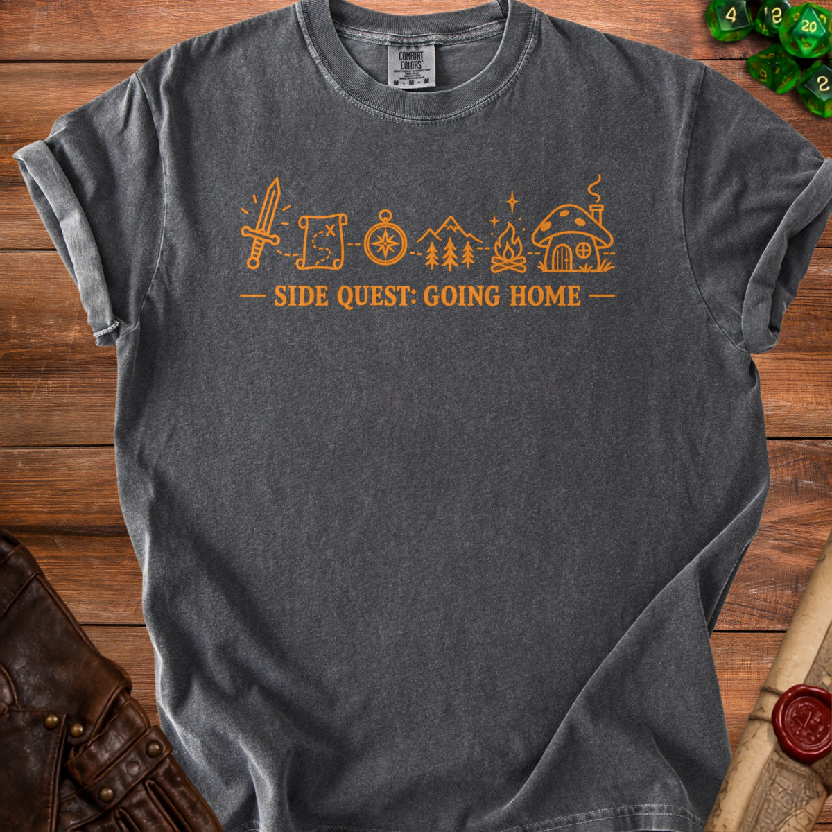 Dark grey t-shirt with orange graphic of sword, map, compass, trees, campfire, and mushroom house.