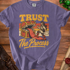 Purple t-shirt with "Trust The Process" and a cartoon adventurer facing a treasure chest with teeth.