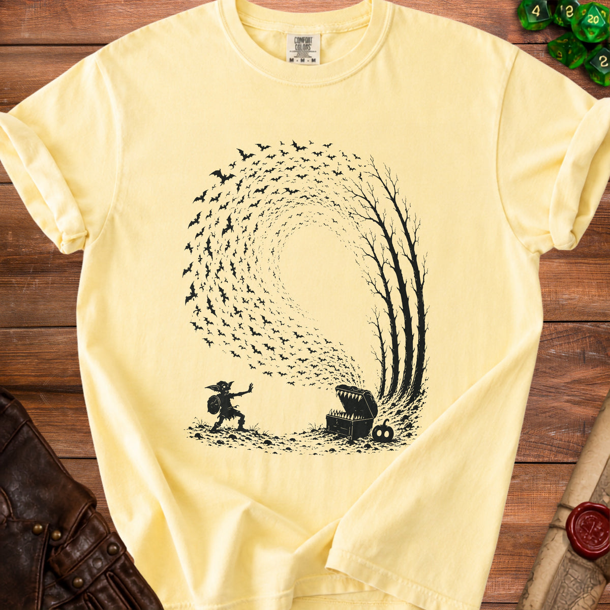 Yellow t-shirt with black graphic of a goblin, treasure chest, and bats swirling around trees.