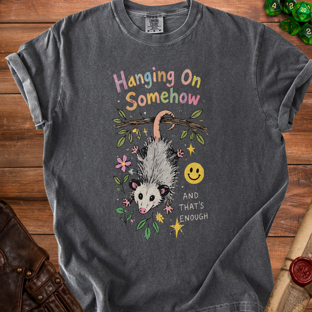 Dark grey t-shirt with a graphic of an opossum hanging from a branch and text.