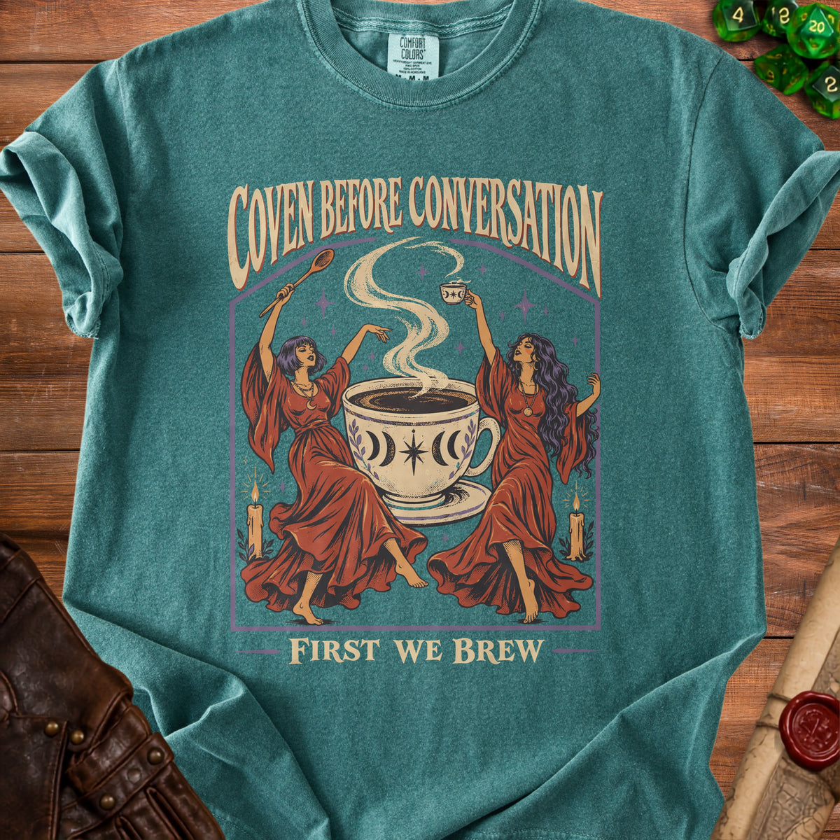 Teal t-shirt with "Coven Before Conversation, First We Brew" text and witchy coffee illustration.