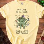 Yellow t-shirt with illustration of a green, multi-armed creature and text "MY LIFE IS A MESS AND I LOVE THE CHAOS".