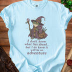 Light blue t-shirt with frog wizard graphic and text "I don't know what lies ahead... but I do know it will be an adventure".