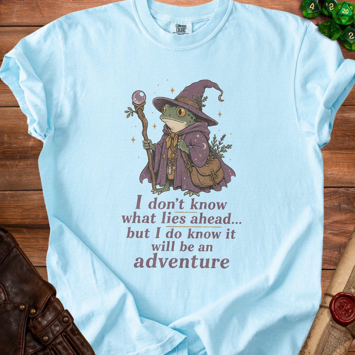 Light blue t-shirt with frog wizard graphic and text "I don't know what lies ahead... but I do know it will be an adventure".