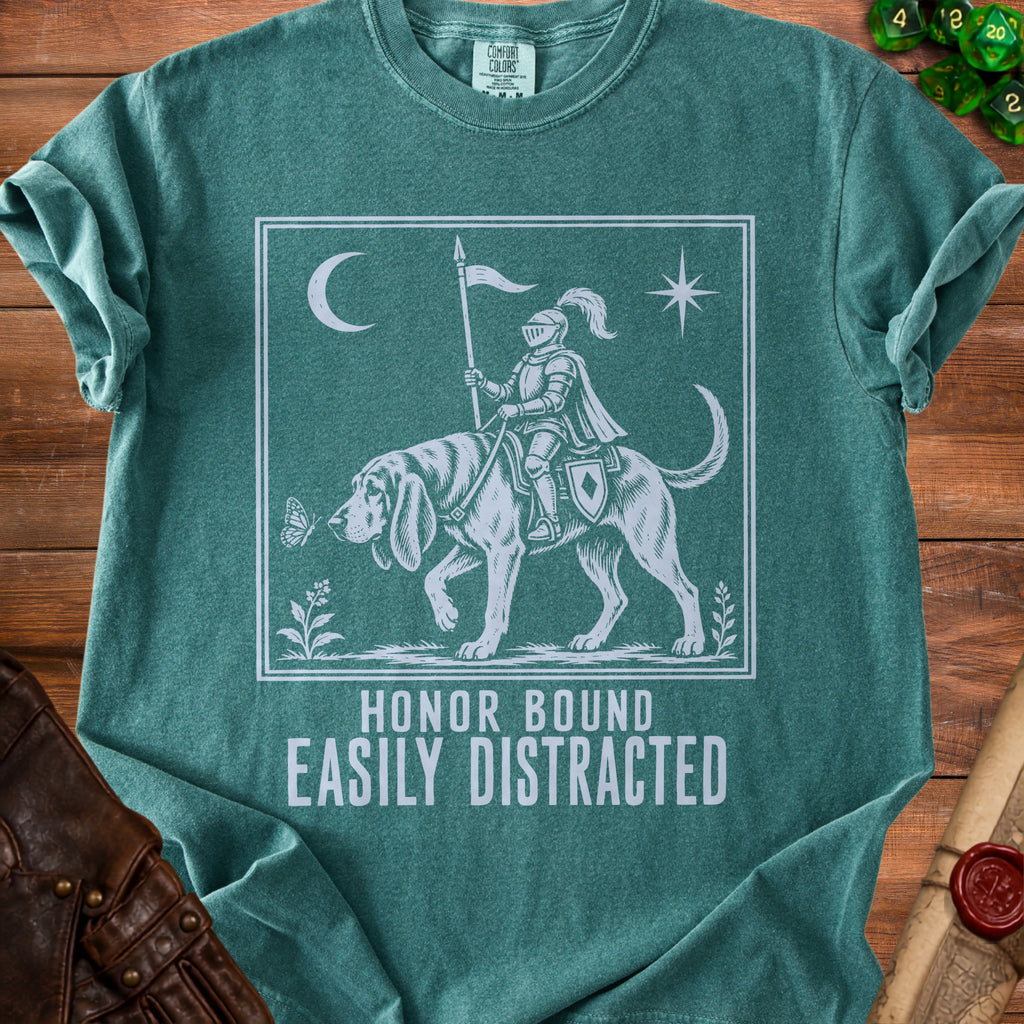 Green t-shirt with a knight on a dog, moon, star, butterfly, and text "HONOR BOUND EASILY DISTRACTED".