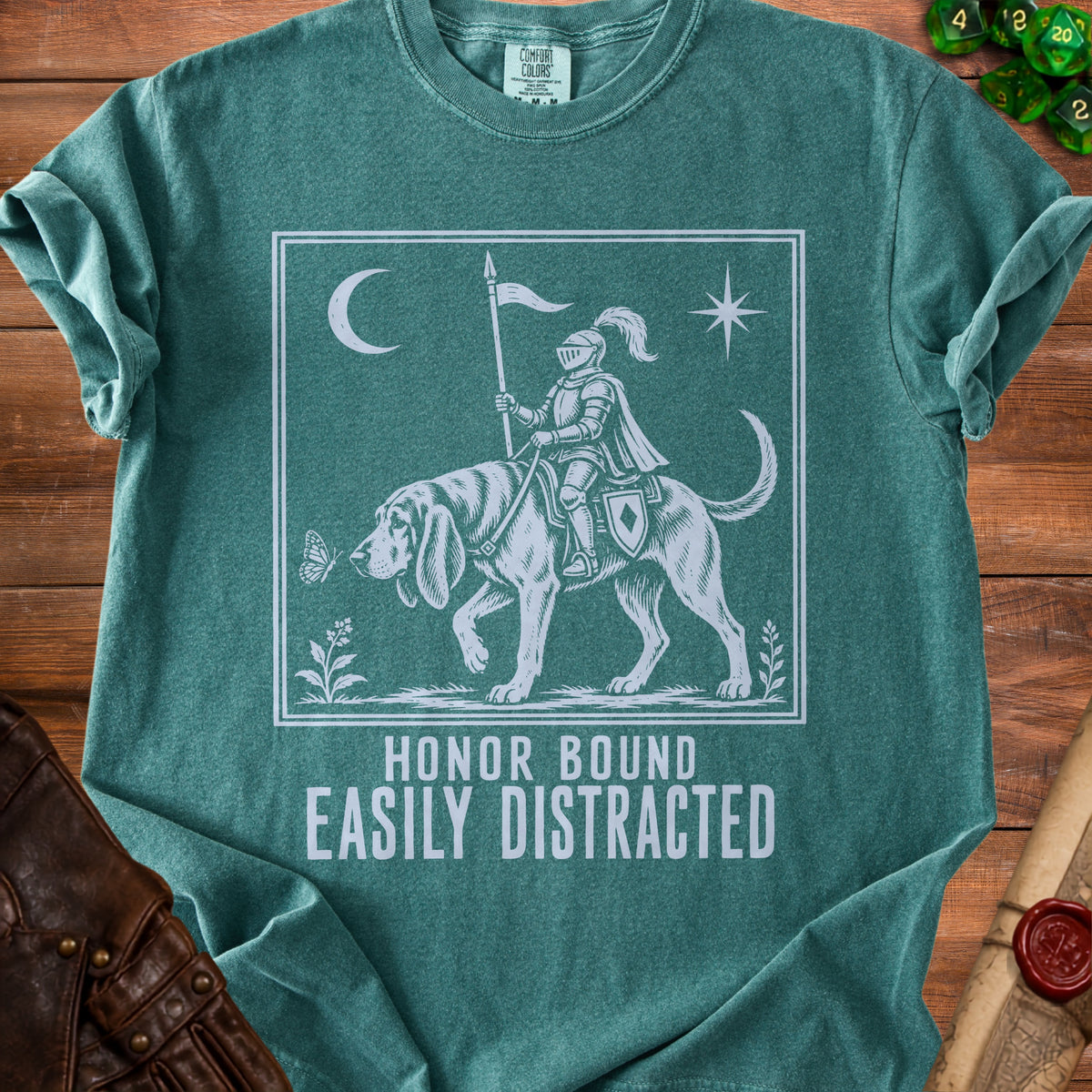 Green t-shirt with a knight on a dog, moon, star, butterfly, and text "HONOR BOUND EASILY DISTRACTED".