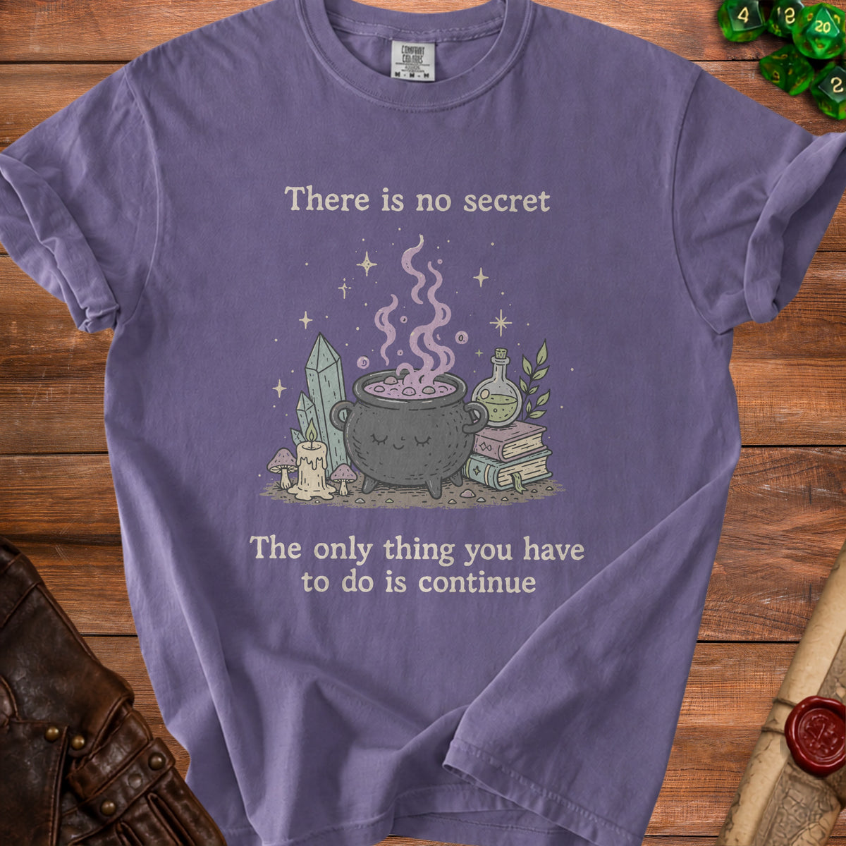Purple t-shirt with illustration of a cauldron and text "There is no secret The only thing you have to do is continue".