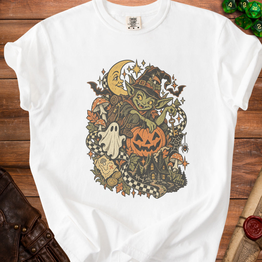 White t-shirt featuring a Halloween goblin with pumpkin, ghost, moon, and spooky house graphic.