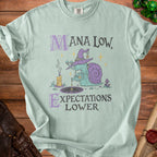 Light blue t-shirt with "MANA LOW, EXPECTATIONS LOWER" and a snail wizard graphic.