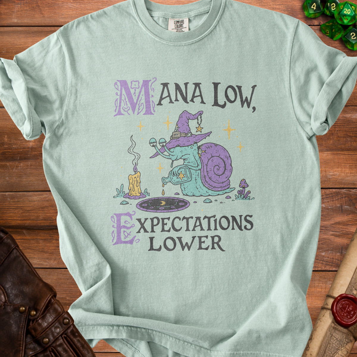 Light blue t-shirt with "MANA LOW, EXPECTATIONS LOWER" and a snail wizard graphic.