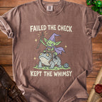 T-shirt with goblin riding frog graphic and text "FAILED THE CHECK KEPT THE WHIMSY".