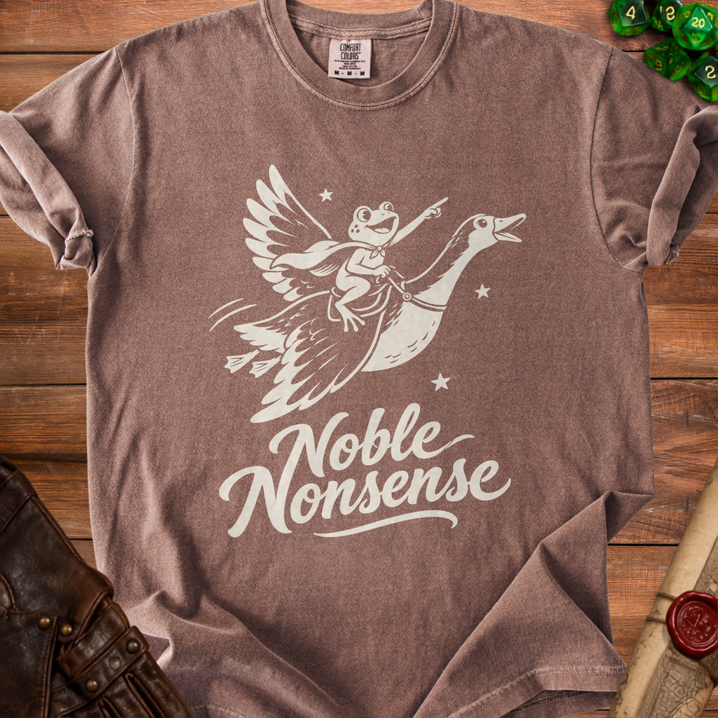 Brown t-shirt featuring a white graphic of a frog wearing a cape riding a flying goose, with the text Noble Nonsense below.