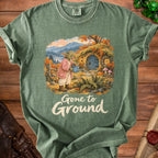 Green t-shirt featuring a creature watering a hobbit-like home with "Gone to Ground" text.