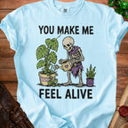 Skeleton watering plants with text "YOU MAKE ME FEEL ALIVE."