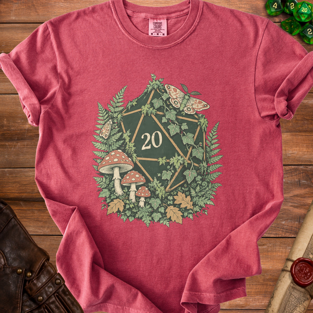 Red t-shirt with a twenty-sided die, mushrooms, ferns, and moths graphic.