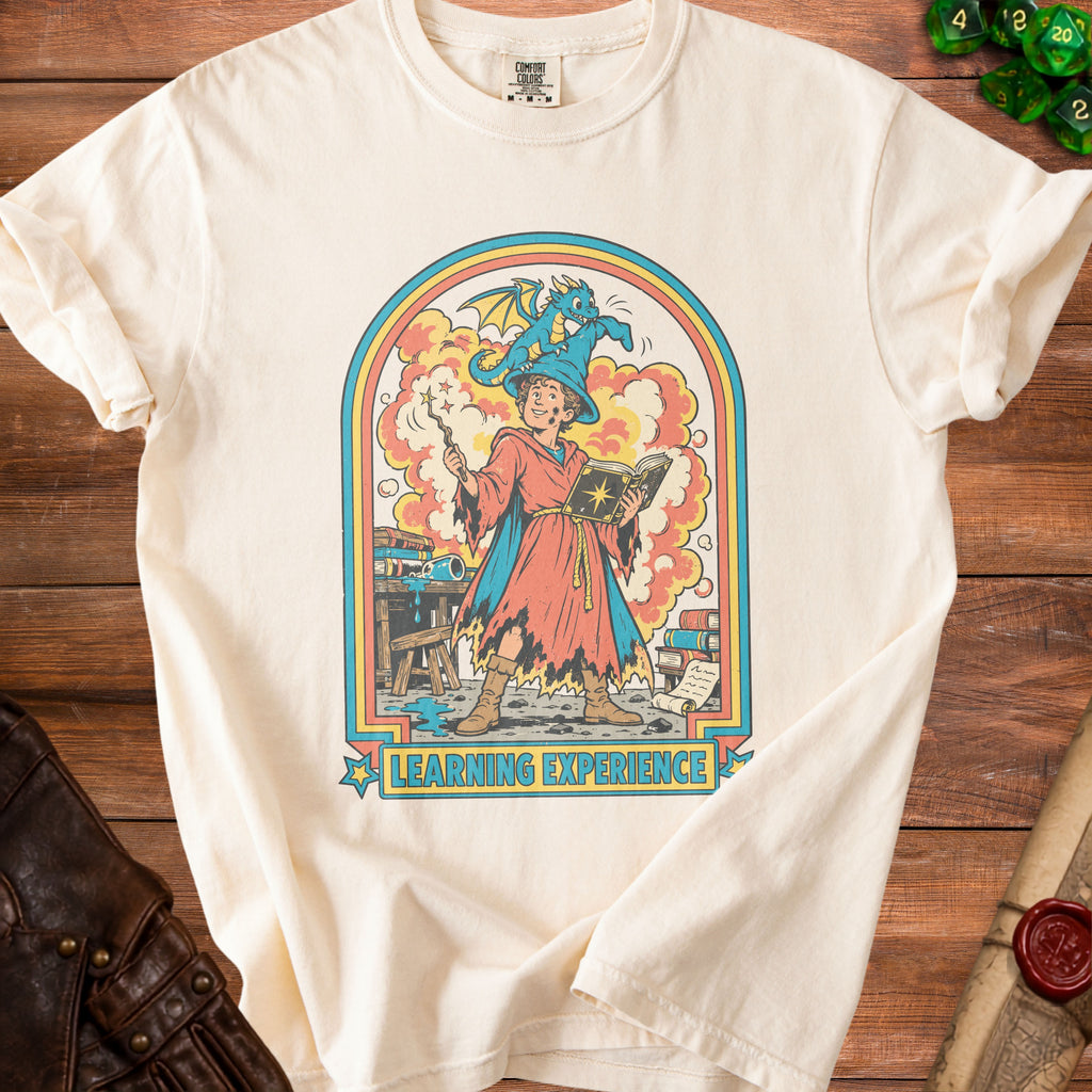 Cream t-shirt with a retro graphic of a young wizard and a dragon, "Learning Experience" text.