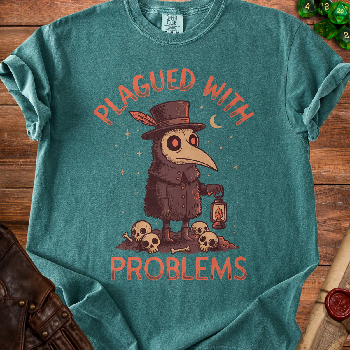 Teal t-shirt with plague doctor holding lantern, skulls, and text "PLAGUED WITH PROBLEMS".