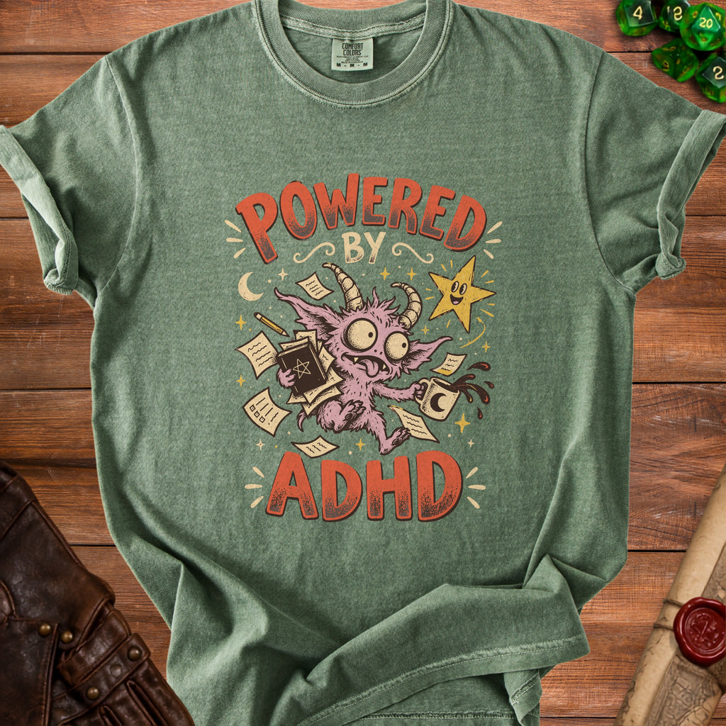 Green t-shirt with graphic "Powered by ADHD" featuring a monster and coffee cup.