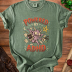 Green t-shirt with graphic "Powered by ADHD" featuring a monster and coffee cup.