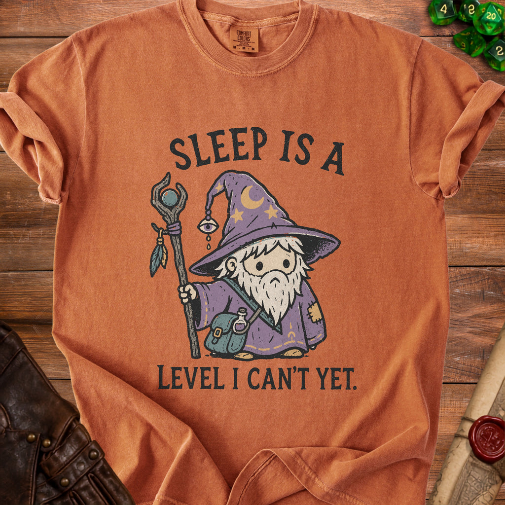 Orange t-shirt with a graphic of a gnome wizard and text "SLEEP IS A LEVEL I CAN'T YET."