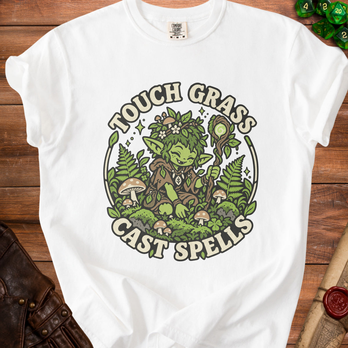 White t-shirt with "Touch Grass Cast Spells" graphic of a green creature holding a staff.