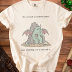 Cream t-shirt with a bored dragon on a rock throne and text.