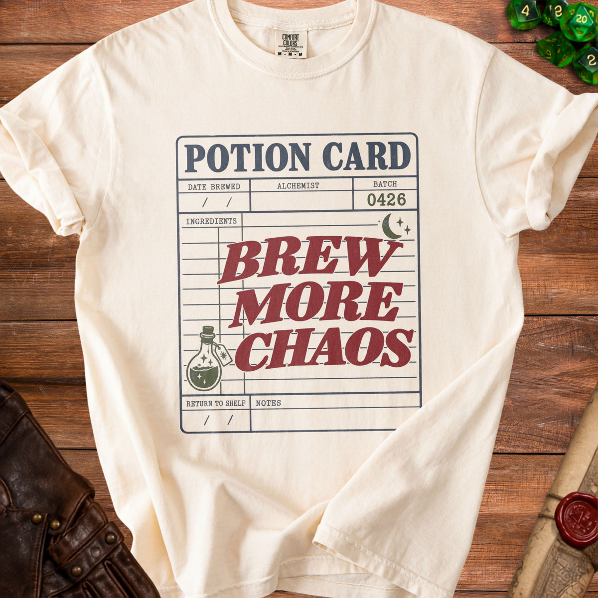 Cream t-shirt with "Potion Card Brew More Chaos" graphic.