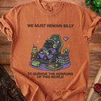 T-shirt with black cat gamer text: We Must Remain Silly to Survive the Horrors of This World.