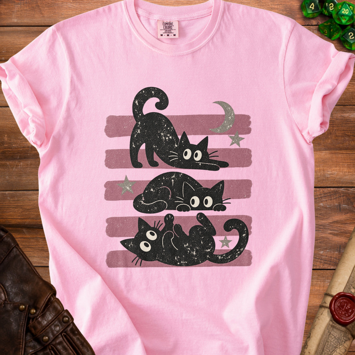 Pink t-shirt with three black cats, moon, stars, and stripes graphic.