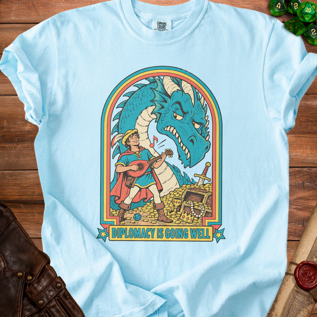 Light blue t-shirt with a blue dragon, bard, and treasure chest graphic reading "DIPLOMACY IS GOING WELL".