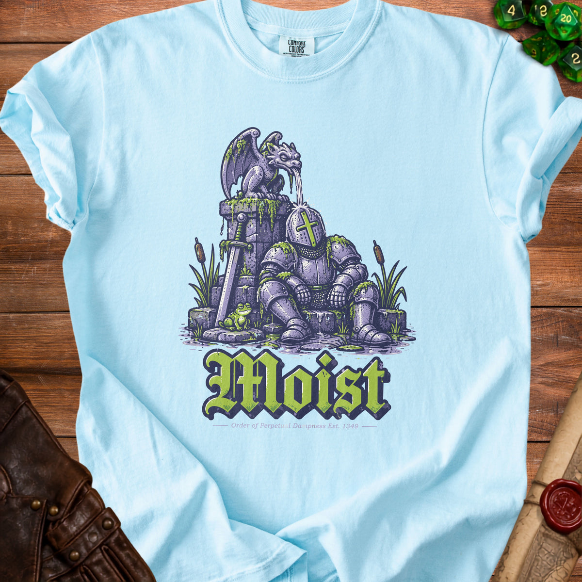 Light blue t-shirt with a knight, gargoyle, frog, and the word "Moist."