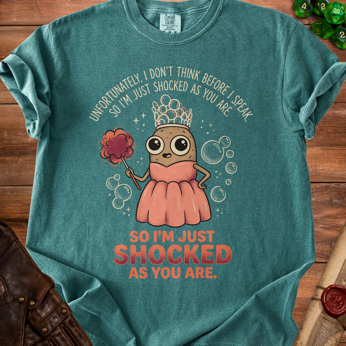 Teal shirt with a cartoon potato wearing a crown and dress, holding a puff, with text.
