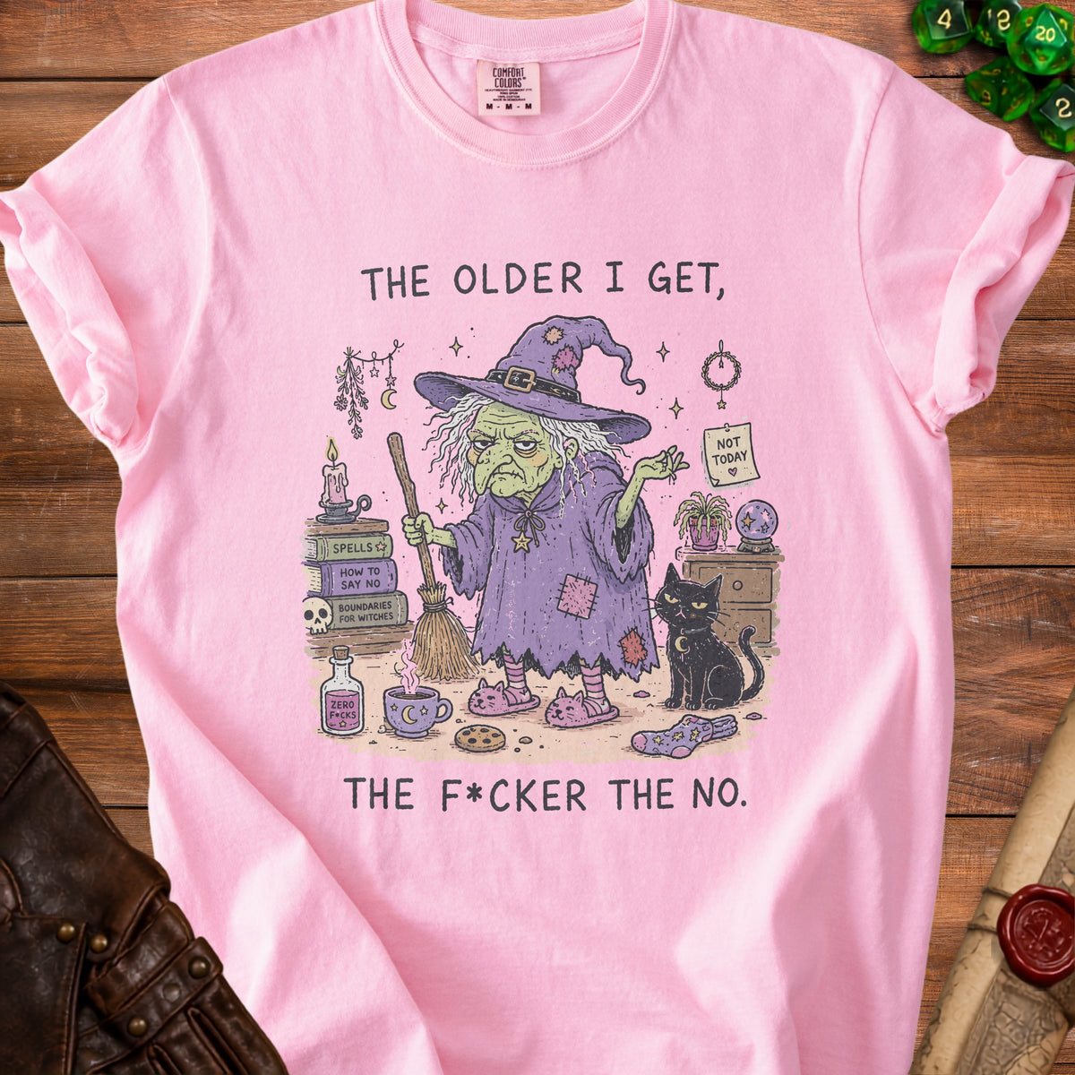 Pink t-shirt with illustration of a witch, black cat, books, potion, and text.