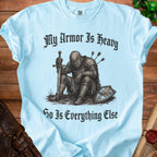 Light blue t-shirt with knight illustration and text "My Armor Is Heavy So Is Everything Else."