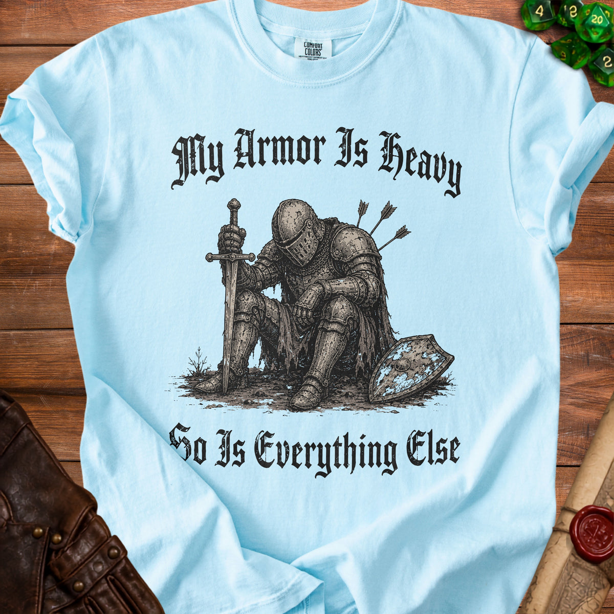 Light blue t-shirt with knight illustration and text "My Armor Is Heavy So Is Everything Else."