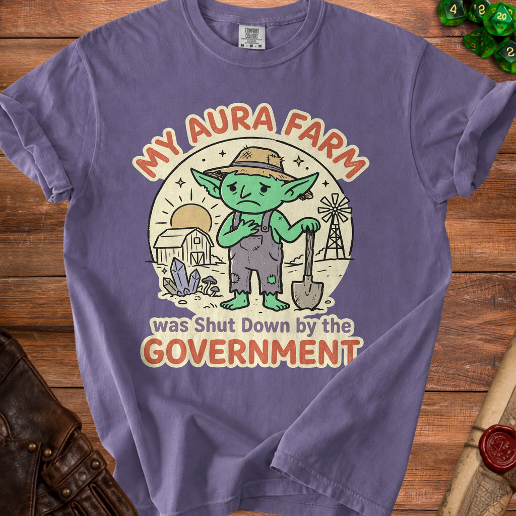 Purple t-shirt with a distressed graphic of a sad goblin farmer and text "My Aura Farm was Shut Down by the Government".