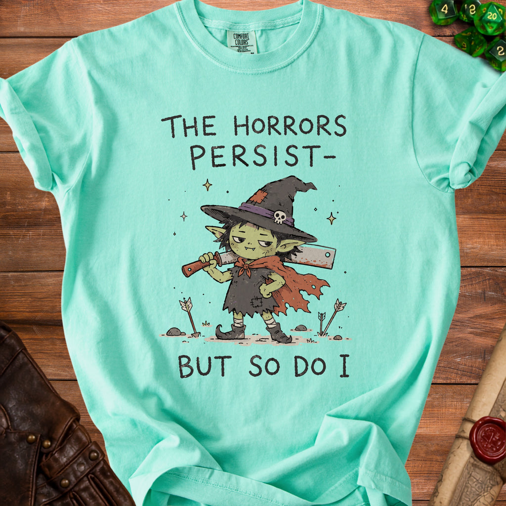Mint t-shirt with illustration of a goblin holding a cleaver and text "The Horrors Persist- But So Do I".