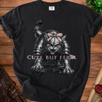 Black t-shirt with a fierce cat in armor wearing a pink bow and text "CUTE BUT FERAL".