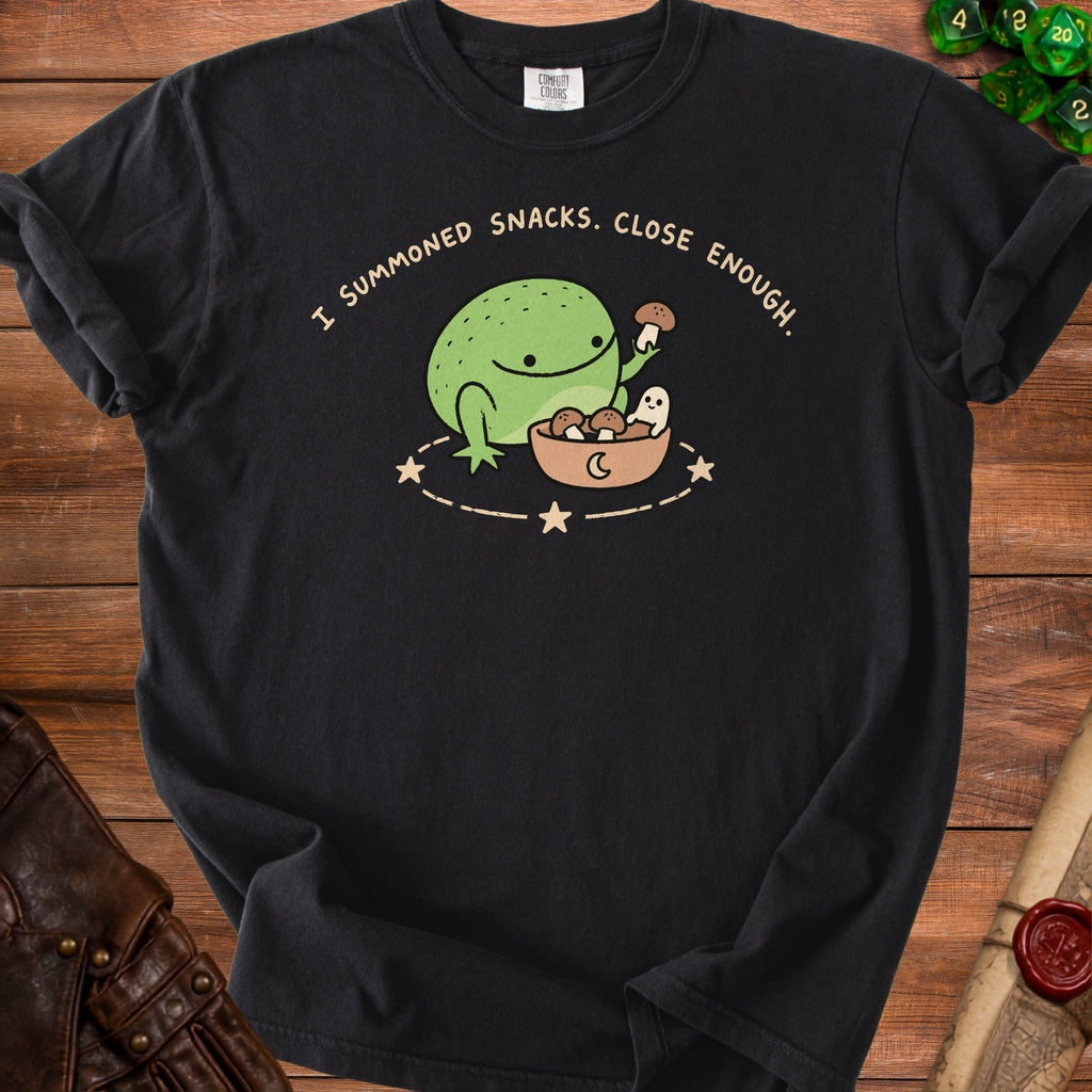 Black t-shirt with a cartoon frog, ghost, and bowl of mushrooms and text "I SUMMONED SNACKS. CLOSE ENOUGH."