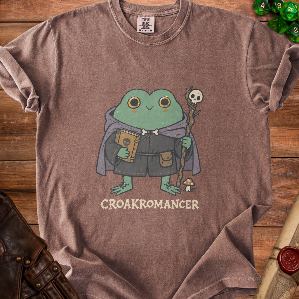 Brown t-shirt with illustration of a frog wizard holding a book and staff, text "CROAKROMANCER".