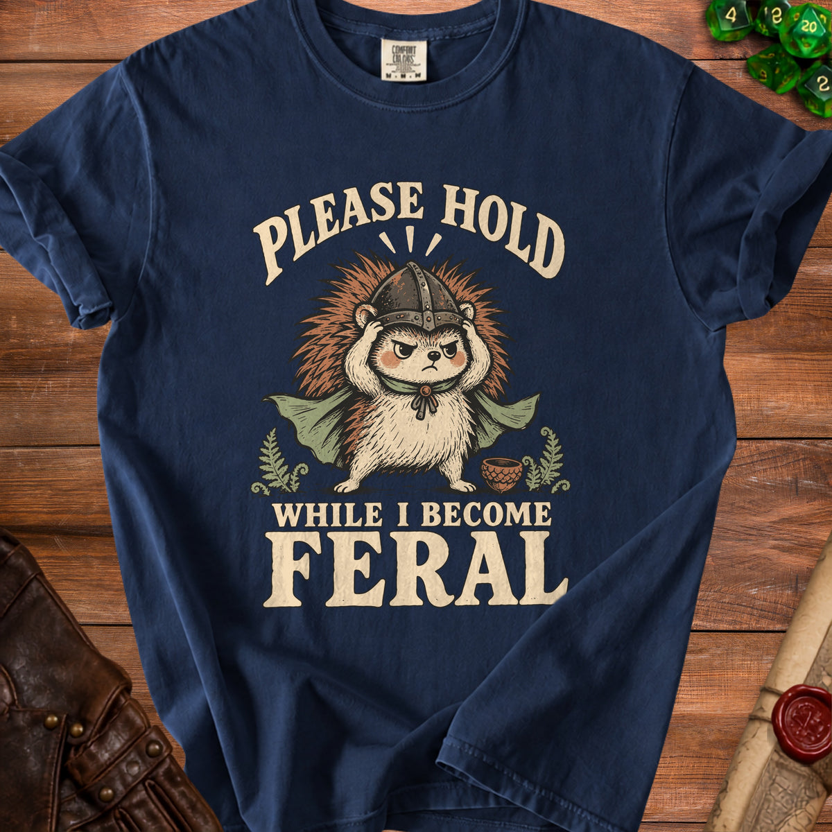 T-shirt graphic with hedgehog wearing helmet, "Please Hold While I Become Feral" text.