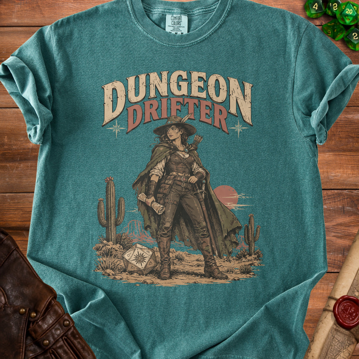A teal crewneck t-shirt featuring a western graphic that says Dungeon Drifter with a character holding a map.