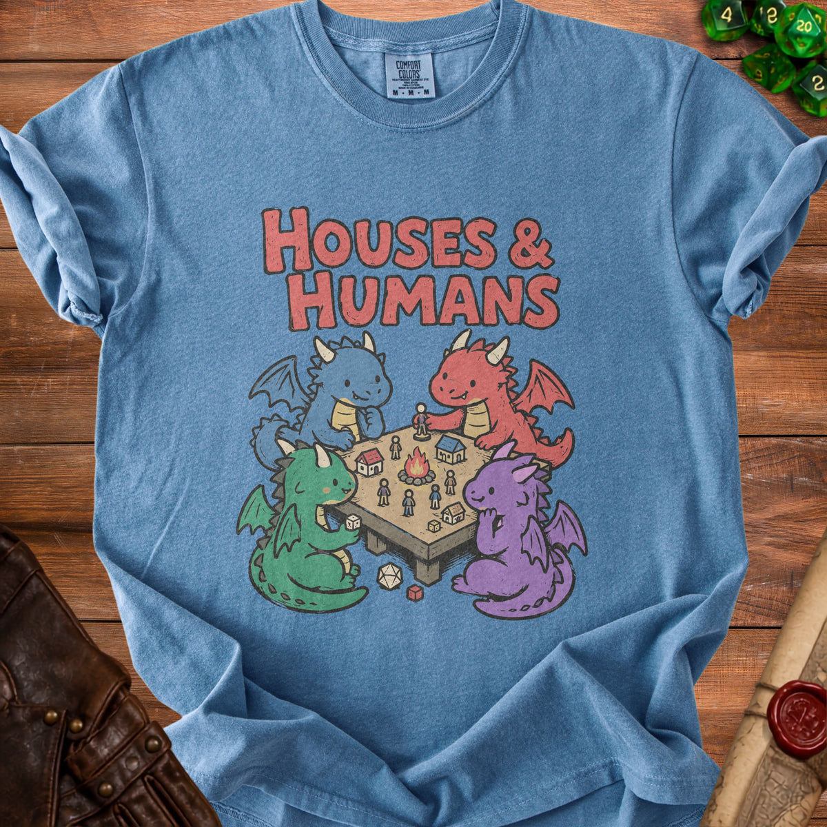 Blue t-shirt with four cartoon dragons playing a tabletop game with dice and figures.