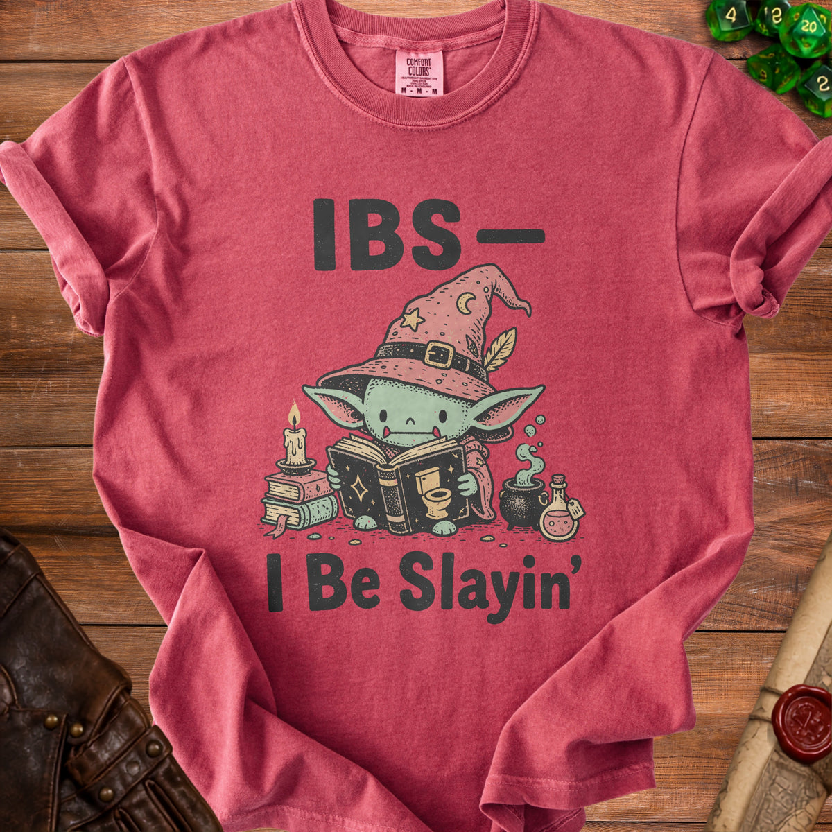 T-shirt with cartoon character wearing a witch hat, reading a book with "IBS- I Be Slayin'" text.