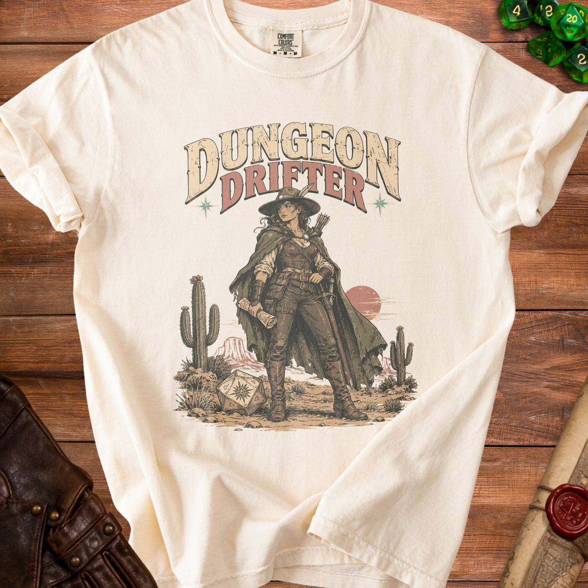 A cream t-shirt with a vintage graphic of a fantasy ranger, cacti, and text reading Dungeon Drifter.