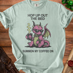 Light blue t-shirt with pink dragon holding coffee and text "Hop Up Out The Bed Summon My Coffee On".