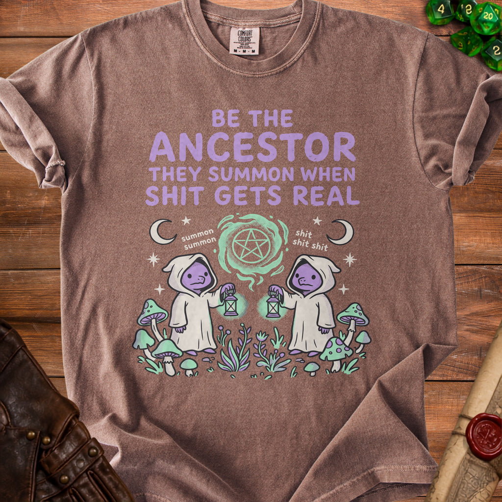 Brown t-shirt with "BE THE ANCESTOR THEY SUMMON WHEN SHIT GETS REAL" text and cartoon characters.