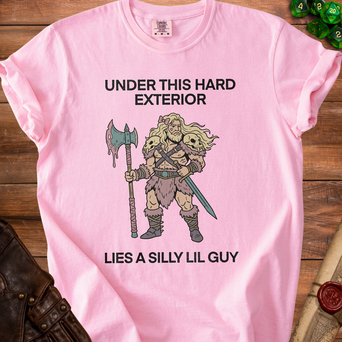 Pink t-shirt with text "UNDER THIS HARD EXTERIOR LIES A SILLY LIL GUY" and barbarian illustration.